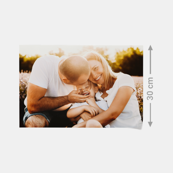 Ein Vater küsst sein lachendes Kind, die Mutter lächelt – festgehalten als Fotoabzug in brillanter Fotoqualität.