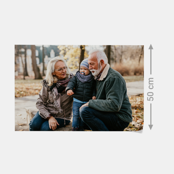 Ein älteres Paar sitzt mit einem Kleinkind im herbstlichen Park – als hochwertiger Fotoabzug mit brillanter Farbqualität.